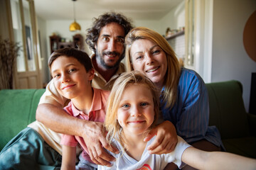 Happy family taking group selfie on couch at home