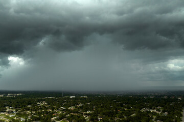Heavy rain falling down from stormy clouds over rural Florida suburbs. Thunderstorm on dark sky....