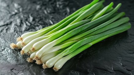 Bunch of fresh green onions lying on black stone surface