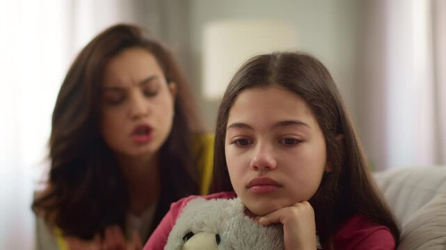Angry furious Caucasian woman female shouting mother mom yelling parent argument quarrel fighting with little girl sister crying kid daughter cry hug toy indoor room. Family relationship child abuse