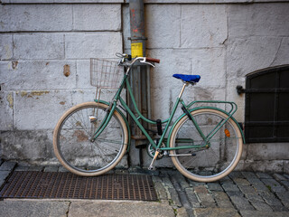 Green Bike Parked against Post on Cobbled Street