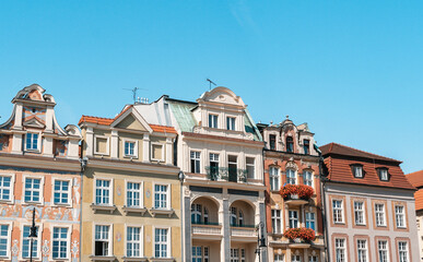 Fototapeta premium Colorful Historic Buildings and Houses on Stary Rynek Square in Poznań, Poland, with a Blue Sky and Mural Art