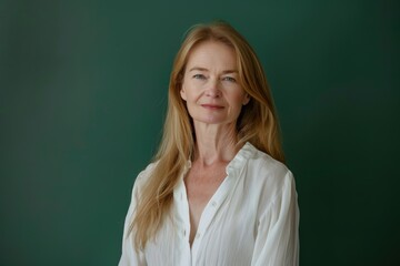 Fototapeta premium Professional Woman with Long Blonde Hair in White Blouse Against Green Background for Corporate Use