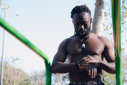 Man training in the park is looking at the time on the watch