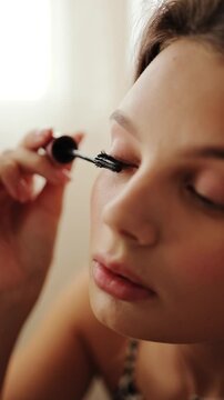 Close up portrait of a beautiful girl paints eyelashes with mascara, decorative cosmetics, blog, tutorial, reflection in the mirror, beauty, fashion and care, mascara brush