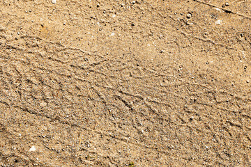 Sand tyre mark background. Tire track shape. Trail lines on dry brown sand pattern. Road construction site backdrop. Heavy machinery imprint. Vehicle wheel shape.