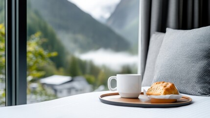 Enjoy a peaceful moment with a cup of coffee and a pastry set on a tray, offering a stunning view of misty mountains and lush greenery from the bedroom window.
