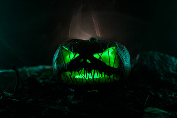 A dark silhouette of a Halloween pumpkin with sharp, needle-like teeth and eyes sewn shut with...