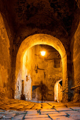 An enchanting and beautifully arched passageway that is softly illuminated inside an ancient stone...