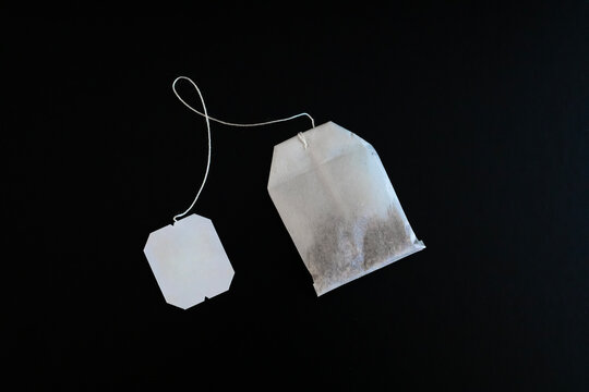 single tea bag flat overhead on black background angled