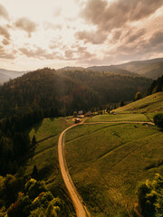 The breathtaking view features stunning rolling hills and a charming, winding road highlighted by the golden hour light