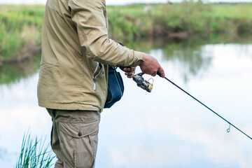 A man catches fish with a spinning rod on the river bank