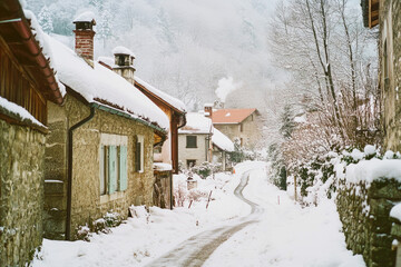 Fototapeta premium A quaint village awakens to a snowy morning with smoke rising from cozy chimneys along a quiet street