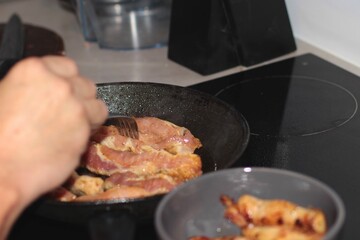 Pieces of meat are being baked in a pan in the kitchen.