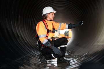 Engineers working inside a large steel pipe, constructing a pipeline for transporting oil, natural...