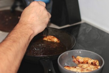 Pieces of meat are being baked in a pan in the kitchen.
