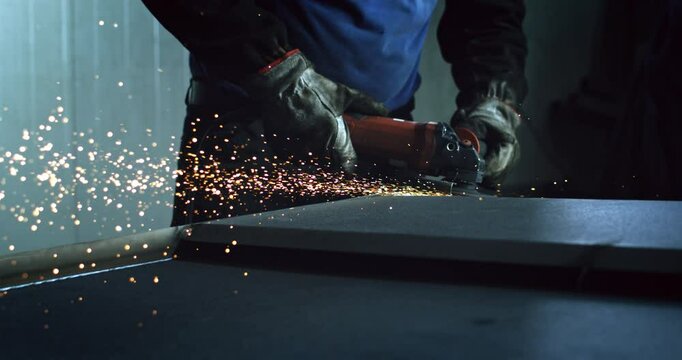 Super slow motion close up of blacksmith welder is smoothing metal steel with industrial angle grinder with flying sparks in workshop at 1000 fps.