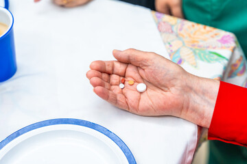 Hand of elder woman with pills and painkillers at geriatrics