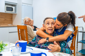 Obraz premium Nurse kissing to a senior woman in the nursing home