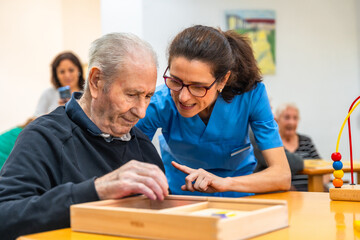 Senior man and caregiver playing skill memory games at geriatrics