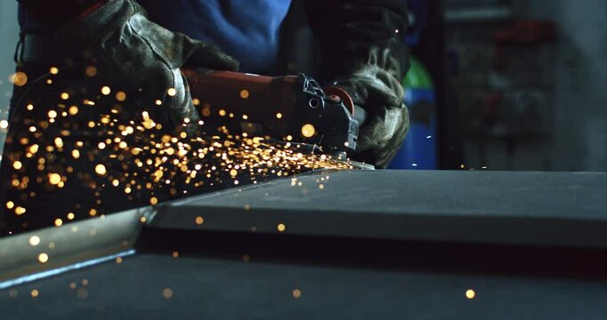 Super slow motion close up of blacksmith welder is smoothing metal steel with industrial angle grinder with flying sparks in workshop at 1000 fps.