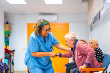 Nurse helping to stand up to senior woman at geriatrics