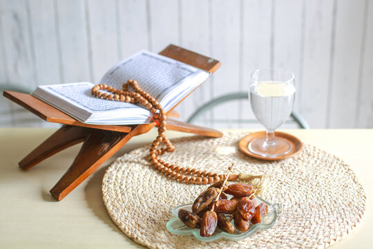 Display of a Misbaha on the Quran next to a glass of water and a plate of dates at iftar time