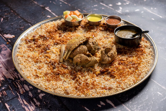 Flat lay of mutton madfoon mandi with vegetables and sauces