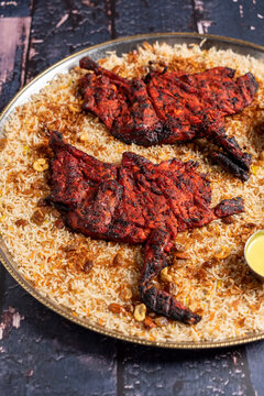 Grilled chicken mandi with a side of vegetables and sauces