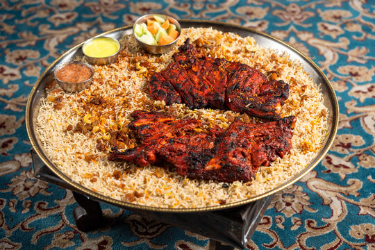 Grilled chicken mandi with a side of vegetables and sauces