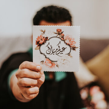 Person holding greeting card that says Eid Moubarak