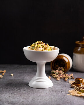 Ummali dessert with pistachios presented in a white ceramic bowl