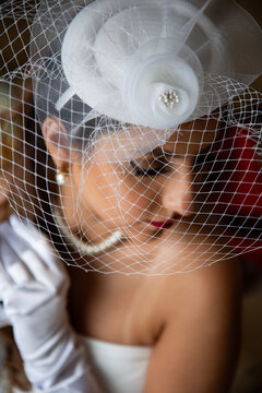 Woman wearing white fishnet rose headpiece and pearl accessories