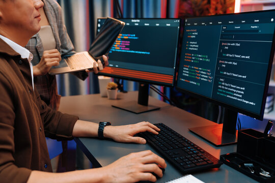 Serious of IT developers discussing intelligent website development coder system running data online two screens with laptop showing information network at neon light room at modern office. Infobahn.