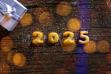 2025, the year 2025 written in bread letters on a wood pattern background.