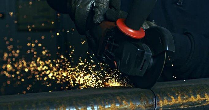 Super slow motion macro of blacksmith welder is working metal steel with industrial angle grinder with flying sparks in workshop at 1000 fps.