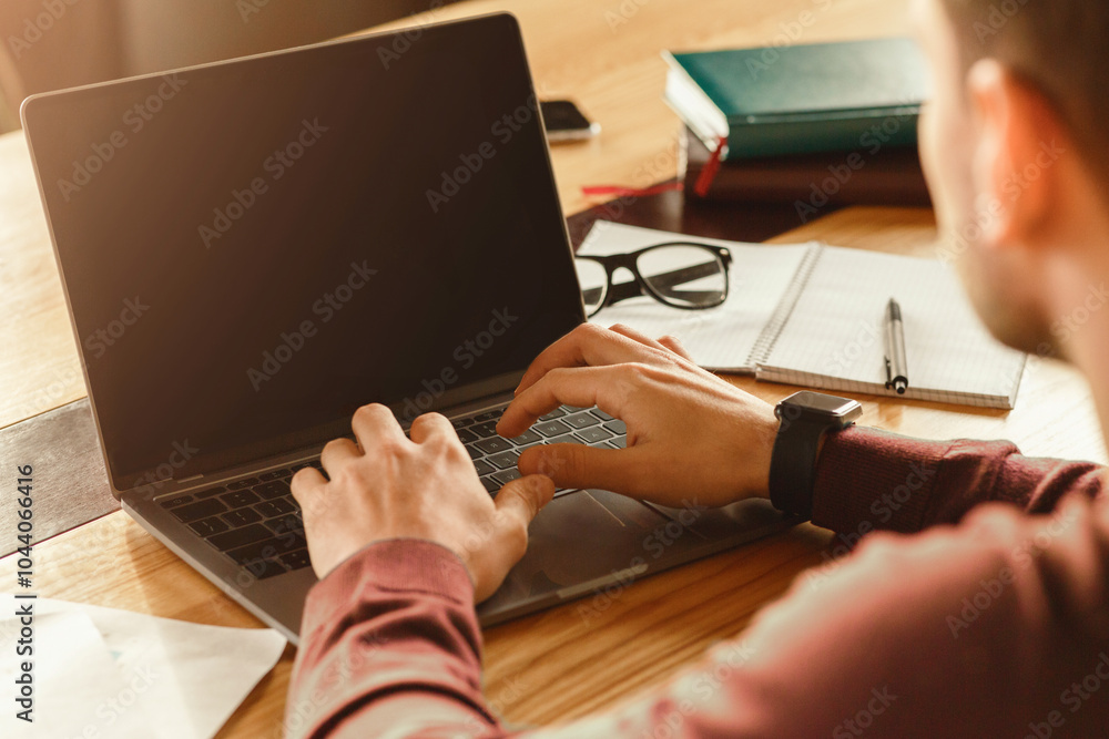 Poster unrecognizable man working on laptop sitting in modern office. computer work. cropped, selective foc