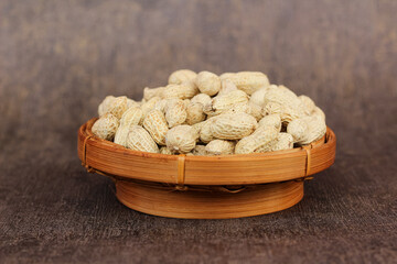 Unpeeled peanuts in a container. close up of salted shell peanuts.