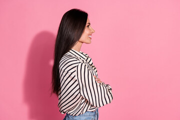 Confident young woman in striped shirt with brunette hair against pink background, showcasing casual style and positive mood