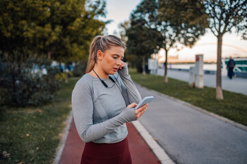 Young sporty woman using smartphone after running in the city park