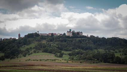 A hillside with a castle in the distance and a cloudy sky