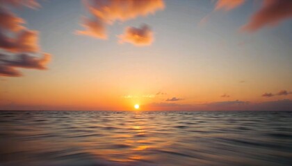 Obraz premium A beautiful sunset over the ocean, with the sun reflecting on the calm water. The sky is filled with warm, vibrant colors of orange and red, creating a serene and peaceful atmosphere