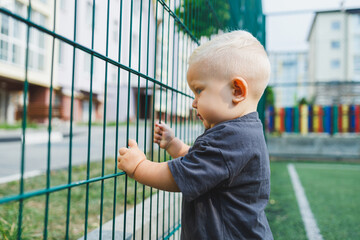 Emotional cute toddler boy on a walk in the park. A 1-year-old boy is running and smiling.