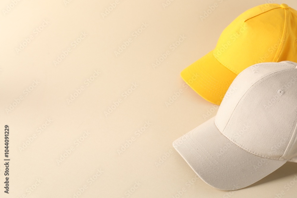 Poster Stylish baseball caps on beige background. Mockup for design