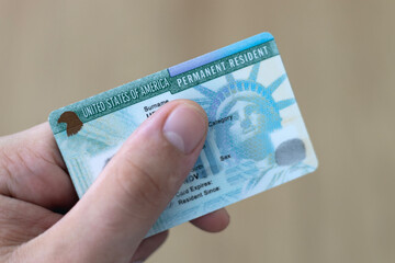 Man holding US permanent resident (green) with his hand. Immigration concept	
