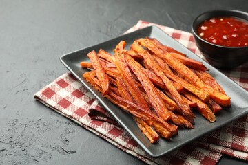 Delicious sweet potato fries with sauce on black table, closeup