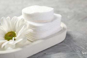 Clean cotton pads and flower on grey table, closeup