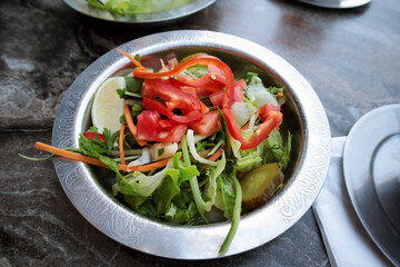 Appetizing salad made of lettuce, capia pepper, pickle and tomato served in a copper plate