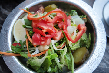 Appetizing salad made of lettuce, capia pepper, pickle and tomato served in a copper plate