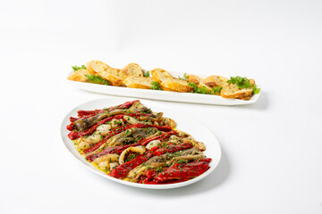 Roasted onions, eggplants and peppers on a platter with toast points in background